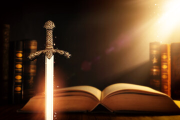 photo of sword and old books over dark background. Medieval period concept - obrazy, fototapety, plakaty