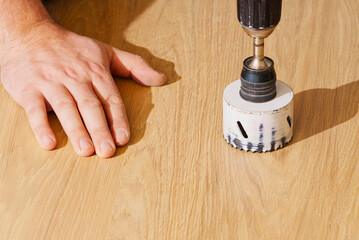 Worker with milling cutter in action at the workshop. Carpenter making holes in the wood board. Man...