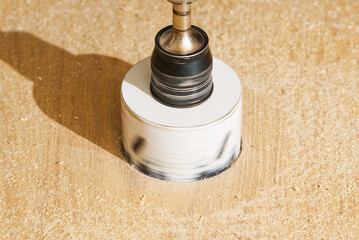 Worker with milling cutter in action at the workshop. Carpenter making holes in the wood board. Man...