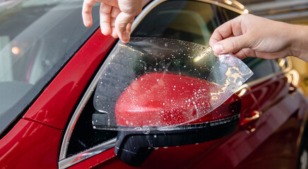 Fototapeta Master man installs vinyl film in risk zone of windshield to protect car body paint obraz