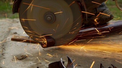 Close-up view of a worker working with angle grinder. Electric wheel grinding on steel structure.
