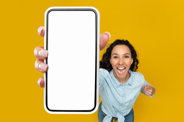 Excited woman showing blank mobile phone screen at studio