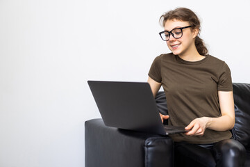 Pensive young woman using laptop computer while sitting on a couch at home