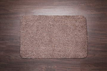 Fototapeta na wymiar Stylish door mat on wooden floor, top view