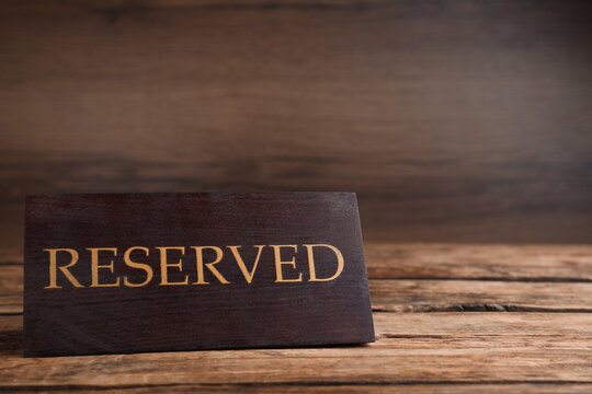 Elegant sign RESERVED on wooden surface, space for text. Table setting element