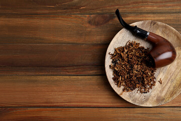 Board with smoking pipe and dry tobacco on wooden table, top view. Space for text