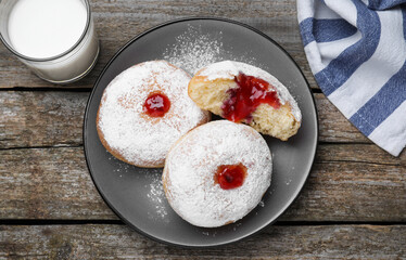 Delicious jelly donuts served with milk on wooden table, flat lay