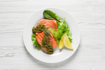 Tasty cooked salmon with pesto sauce on white wooden table, top view