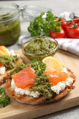 Delicious bruschetta with salmon, cream cheese and pesto sauce on table, closeup
