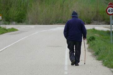 Persona anciana de avanzada edad dando un paseo con la cachaba. 