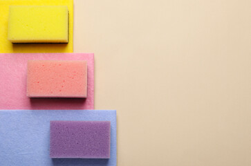 New sponges and rags on beige background, top view. Space for text