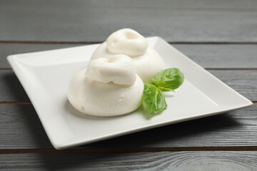 Delicious burrata cheese with basil on grey wooden table