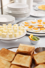 Clean dishware and different meals for breakfast on white table indoors. Buffet service