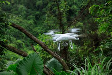 White drone with camera flying in summer forest