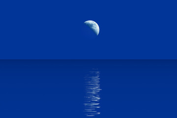 Crescent moon and moonlight path in water blue background