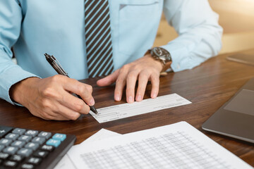 Businessman hands writing and signing check. business, finances and money concept.