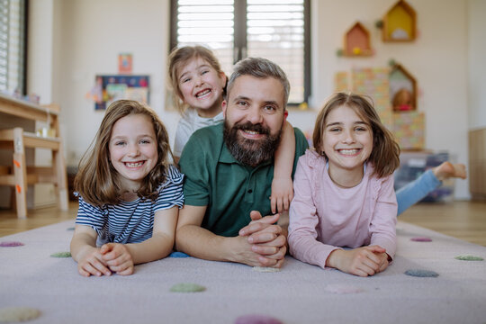 Cheerful father with three little daughters playing together at home.