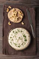 Vegetarian cream cheese made from fermented cashews on dark wooden background. Flat lay