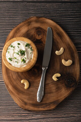 Vegetarian cream cheese made from fermented cashews on dark wooden background. Flat lay