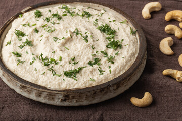 Vegetarian cream cheese made from fermented cashews on dark wooden background. Close-up.