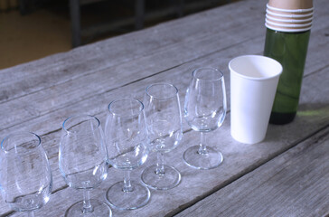 Group wine tasting set up on a large rustic timber table. Wine glasses, waste cup and water bottle with paper cups