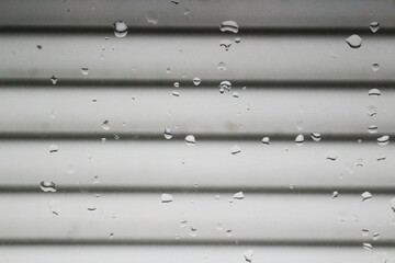 Raindrops on the window with blinds.