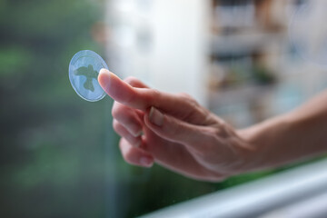 A woman's hand sticks decals on windows for birds. These decals has a special coating that reflects...
