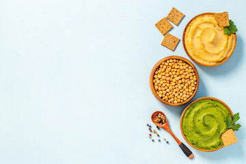 Flatlay of different types of colorful hummus in bowls. Vegan food background