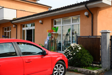 Red car parked near store of household items on sunny day