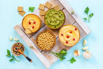 Colorful hummus served with bread snacks and herbs, flat lay
