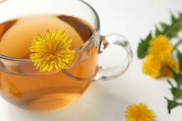 Delicious fresh tea with dandelion flowers on white table, closeup