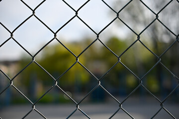 Metal mesh wire fence with blur basketball court background