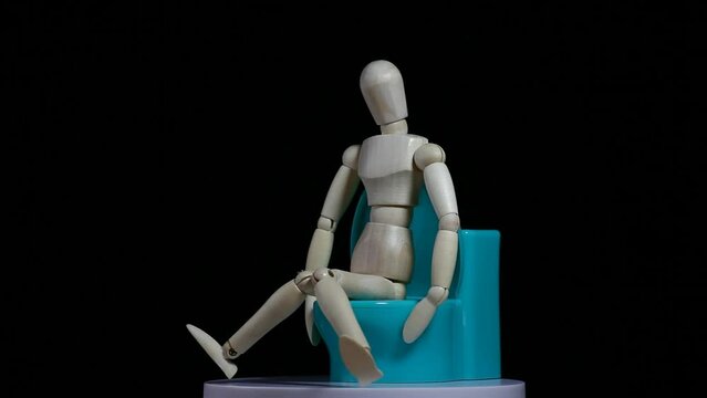 footage of miniature toilet wooden mannequin dark background