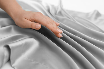 Woman touching smooth silky fabric, closeup view