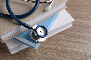 Student textbooks and stethoscope on wooden table, closeup view with space for text Medical...