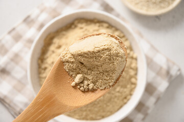 Fototapeta na wymiar Sesame flour in wooden spoon. Close up. Good vegan source of protein, minerals, natural antioxidants and vitamins.