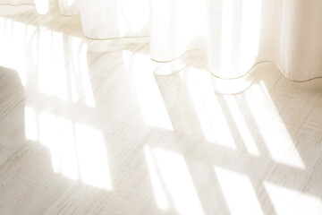 Curtain over sunlit wooden floor in morning