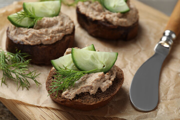 Slices of bread with delicious pate, cucumber and dill on wooden board, closeup