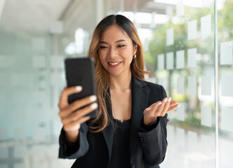 Asian business woman waving fists, got good news on mobile smart phone in office, social media network, video calling, communication.