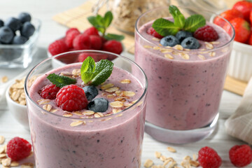 Tasty smoothie with berries, mint and oatmeal on white table, closeup