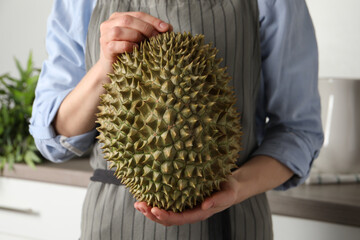 Woman with fresh durian in kitchen, closeup