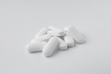 Pile of calcium supplement pills on white background, closeup