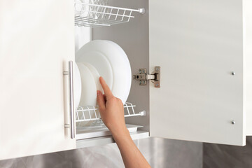 a woman puts a plate on a shelf in the kitchen. close-up