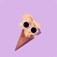 Summer creative layout with melting ice cream cone and white sunglasses on pastel purple...