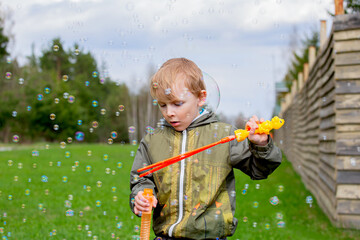 A boy blows soap bubbles on the street