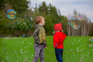 Children playing on the green grass with soap bubbles