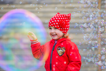 a little smiling girl in soap bubbles