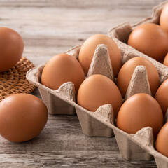 Fresh brown chicken eggs in a kraft paper egg carton.