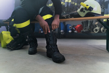 Lowsection of firefighter preparing for action in fire station at night