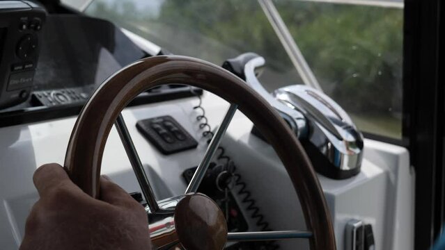 4k slow motion video with a man driving a boat during a cloudy day. Detail view with the gear and the steering wheel.